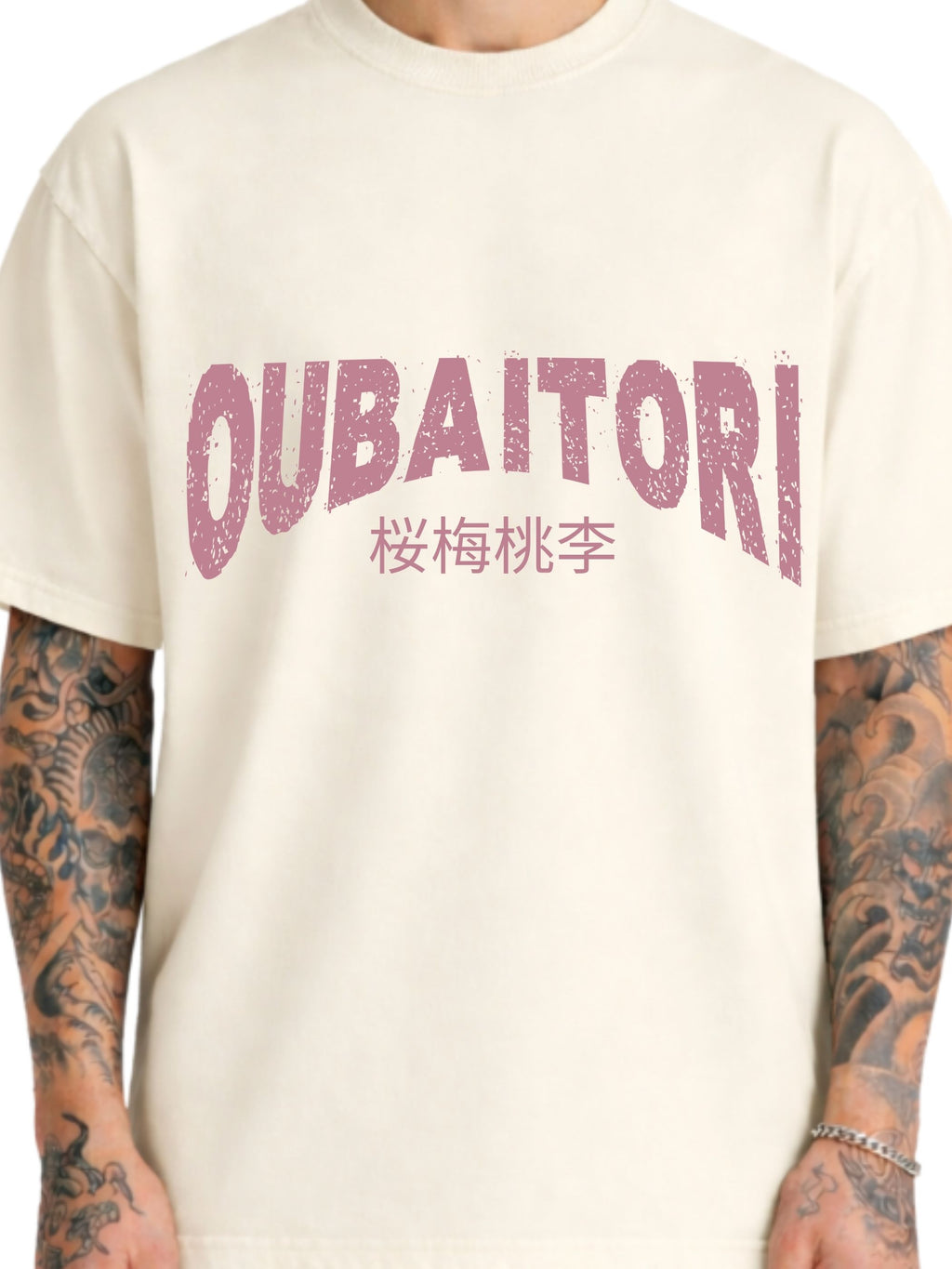 A close-up of a person wearing a cream-colored t-shirt with a distressed pink graphic on the chest that reads 'OUBAITORI' with Japanese characters underneath. 