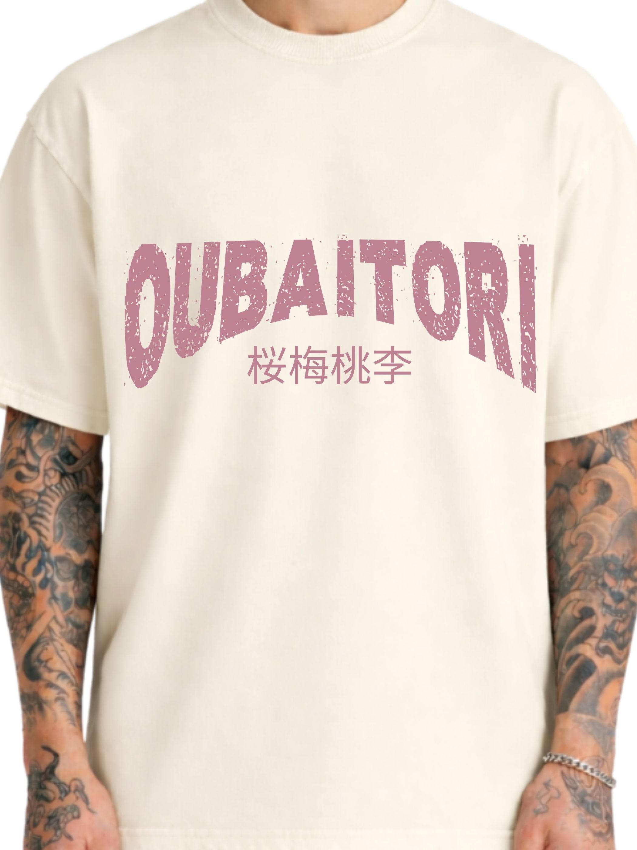 A close-up of a person wearing a cream-colored t-shirt with a distressed pink graphic on the chest that reads 'OUBAITORI' with Japanese characters underneath. 