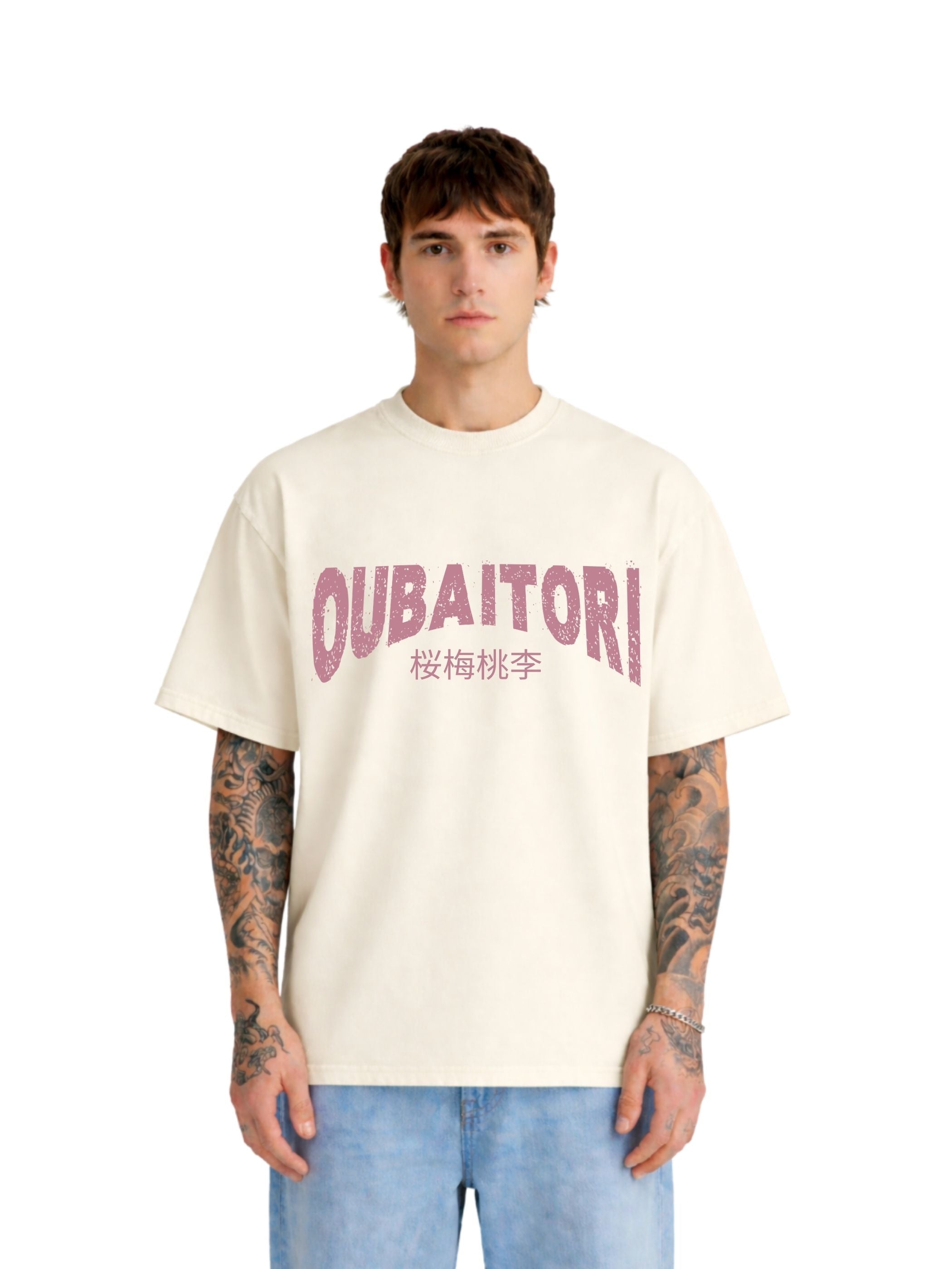A man wearing an oversized cream-colored t-shirt with 'OUBAITORI' and Japanese characters printed in dusty pink across the chest, paired with light blue jeans, set against a plain white background.